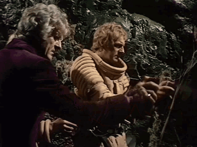 two men are standing next to each other and one is wearing a yellow jacket