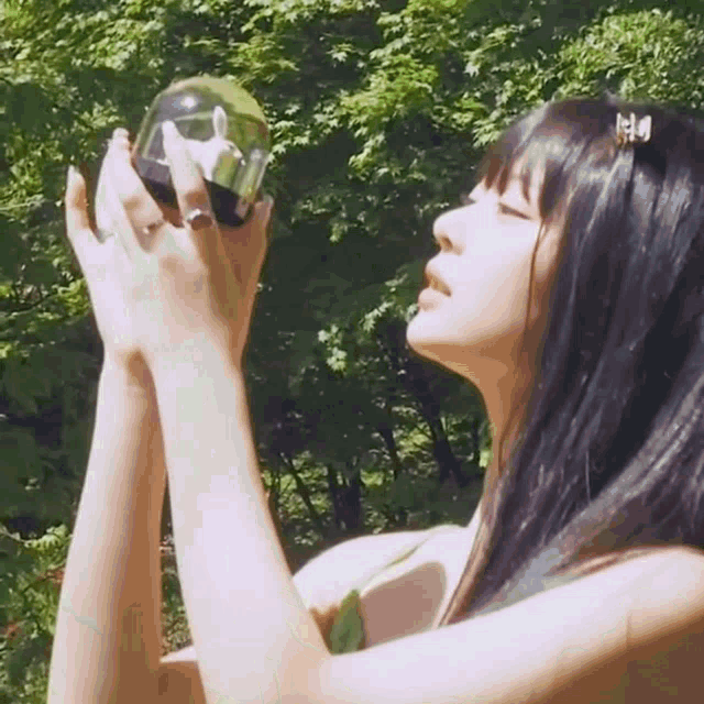 a woman is holding a glass ball in her hands in a park .