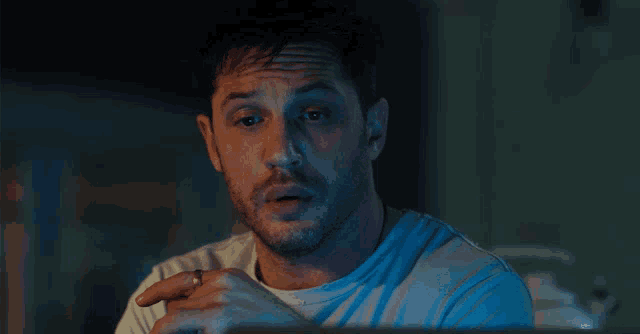 a man with a beard and a ring on his finger looks at something