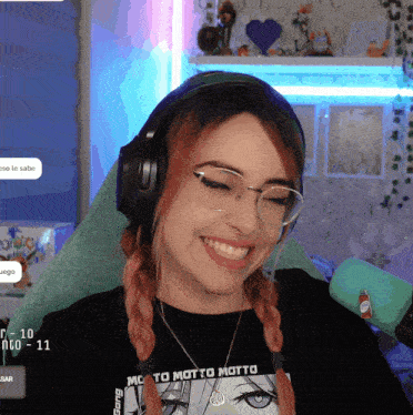 a woman wearing headphones and a shirt that says motto motto is smiling
