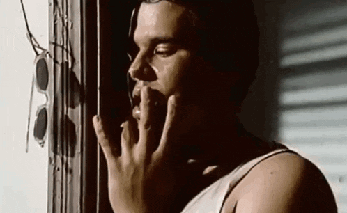 a man is smoking a cigarette while looking out a window .