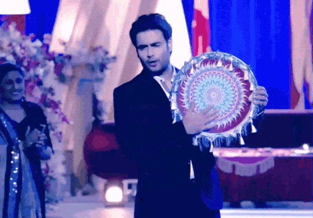 a man in a suit is holding a colorful circular object