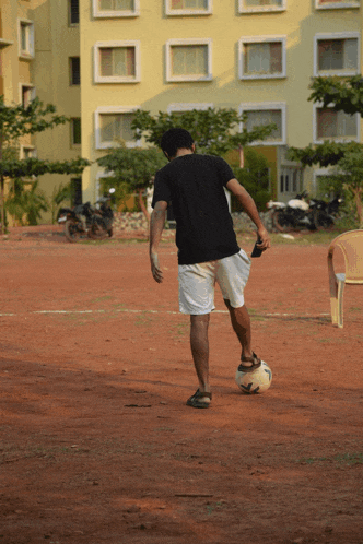 a man is kicking a soccer ball on a dirt field