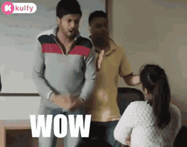 a man is dancing in front of a group of people in a classroom while a woman sits at a desk .
