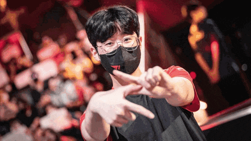 a young man wearing a mask and glasses is making a peace sign with his hands .