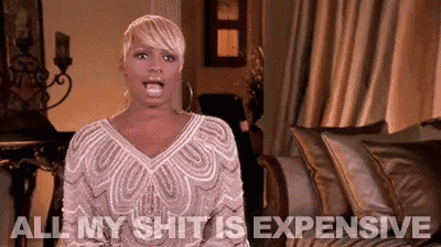 a woman in a white dress is sitting on a couch and saying all my shit is expensive