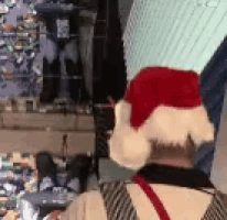 a man wearing a santa hat is standing in front of a display of clothes .