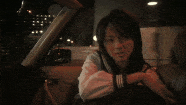 a girl in a school uniform sits in a car