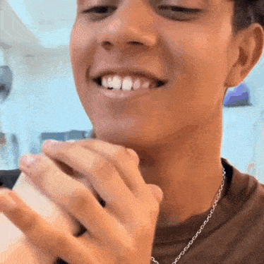 a young man is smiling while holding a cell phone in his hand .