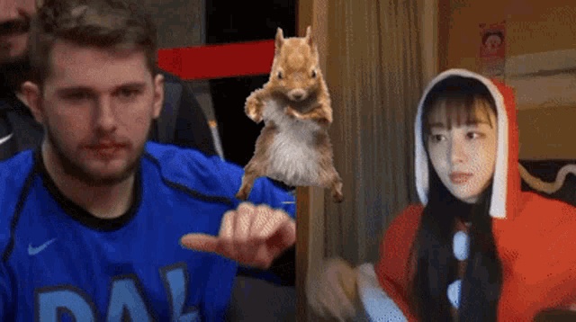 a man wearing a dallas jersey holds a squirrel in his hand