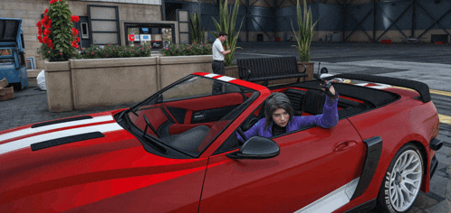 a woman in a purple jacket is sitting in a red convertible sports car