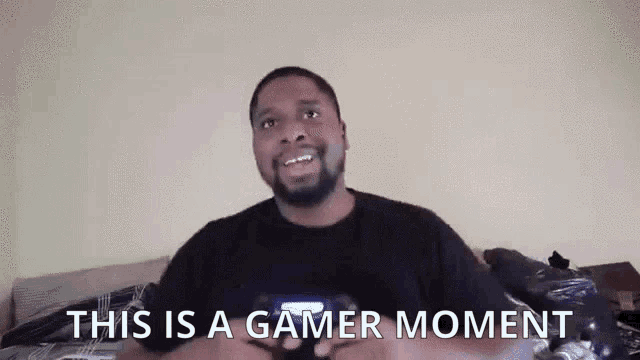 a man holding a video game controller with the words " this is a gamer moment " above him