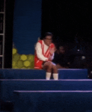 a person in a red and white outfit is sitting on a stage