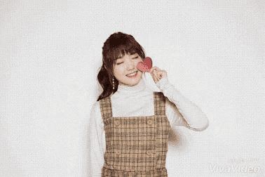 a girl is holding a red heart in her hand and smiling .