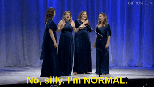 a group of women singing on a stage with the words " no silly i 'm normal " in yellow