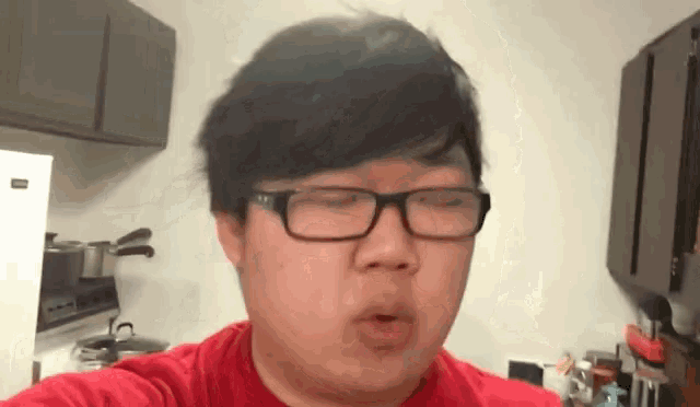 a man wearing glasses and a red shirt is making a funny face .