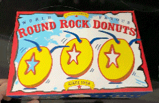 a box of round rock donuts with three donuts in it