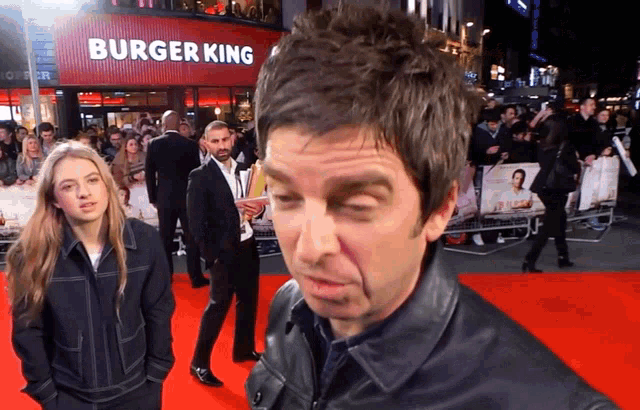 a man standing on a red carpet in front of a burger king sign
