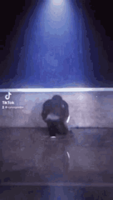 a man is kneeling down in front of a blue light .