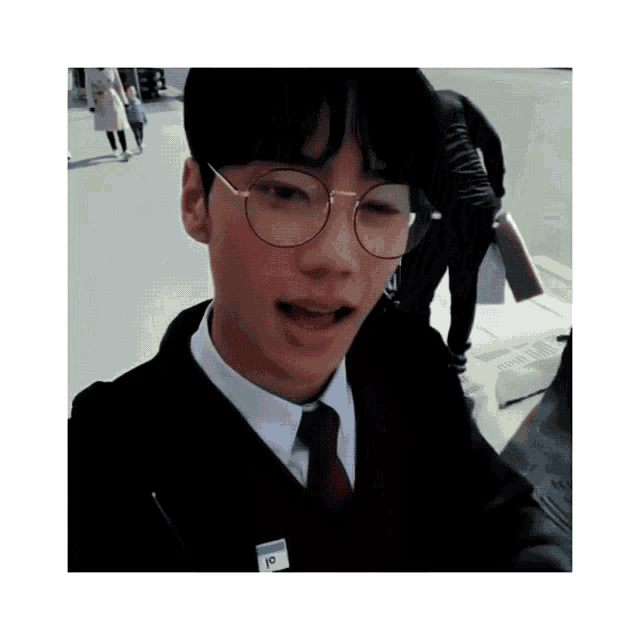 a young man wearing glasses and a name tag that says ' io ' on it