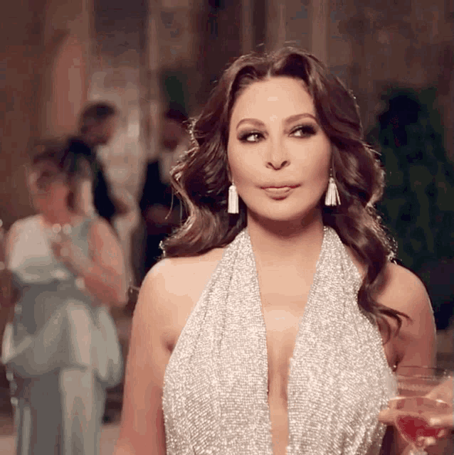 a woman in a silver dress holds a glass of wine in her hand