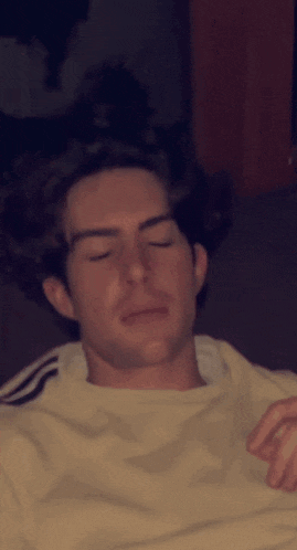 a man with his eyes closed is wearing a white adidas shirt
