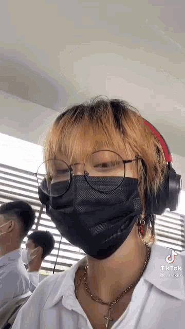 a person wearing a mask and headphones is standing in front of a window .