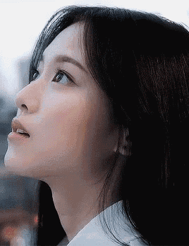 a close up of a woman 's face with a white shirt on looking up .