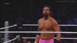 a man is doing a handstand in a wrestling ring while wearing pink shorts .