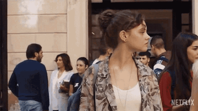 a woman is standing in a crowd of people on a street .
