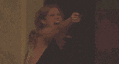 a woman is holding a gun in her hand and shooting it at a man .