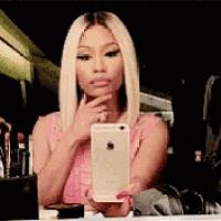 a woman is taking a selfie in front of a mirror while holding a cell phone .