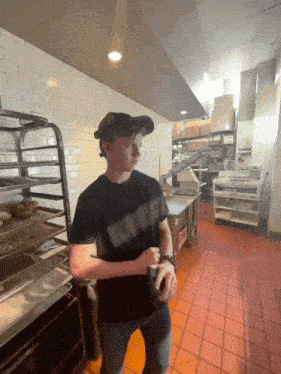 a man in a black shirt stands in a bakery kitchen
