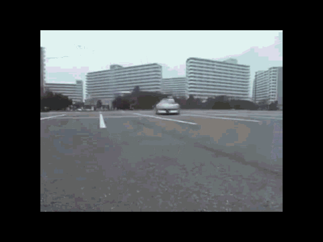 a car is driving down a street in front of a city