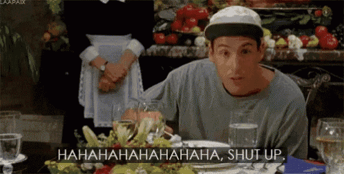 a man in a baseball cap is sitting at a table with a plate of food and glasses of water .