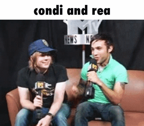 two men are sitting on a couch and one is holding a microphone and the words condi and rea are above them