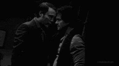 a black and white photo of two men standing next to each other and looking at each other .