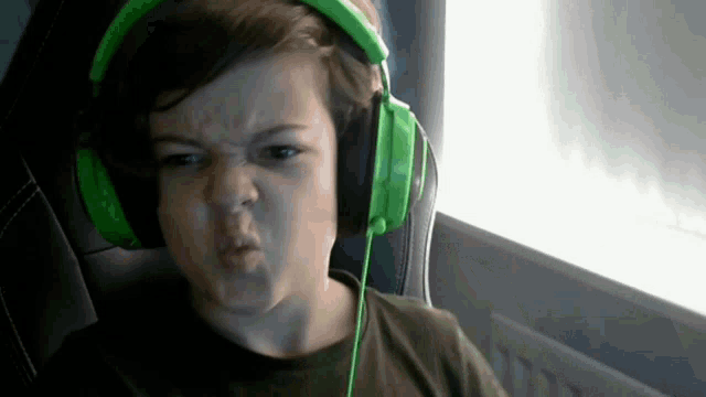 a young boy wearing green headphones makes an angry face