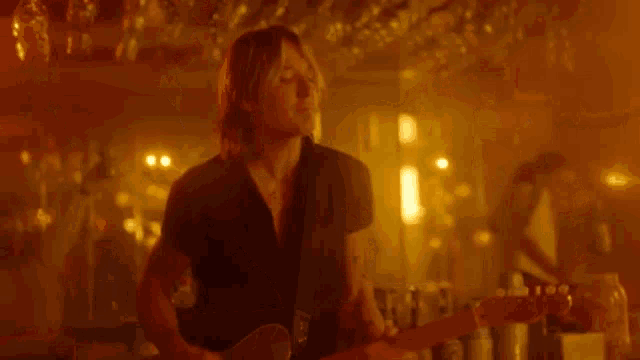 a man is playing a guitar in a dark room .