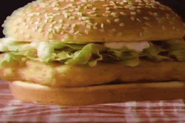 a close up of a chicken sandwich on a checkered cloth