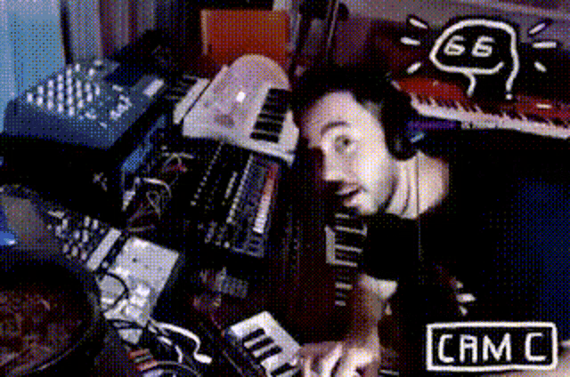 a man wearing headphones is playing a keyboard in a room with a sign that says cam c.