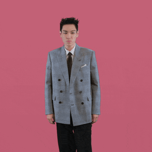 a man in a suit and tie with his arms outstretched against a pink background