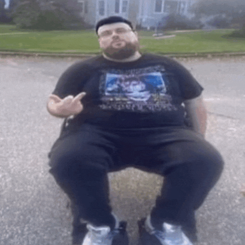 a man with a beard is sitting in a chair and giving a middle finger .
