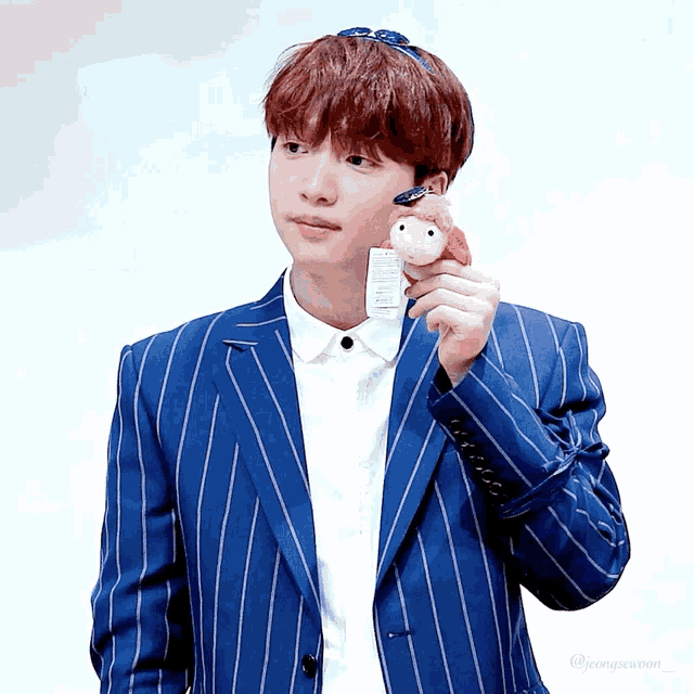 a boy in a blue striped suit holds a stuffed animal