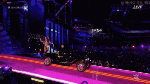 a woman is riding a car on a stage during a wrestling match .
