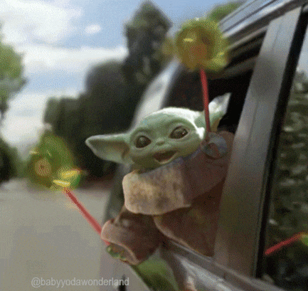 a baby yoda is sticking its head out of the window of a car .