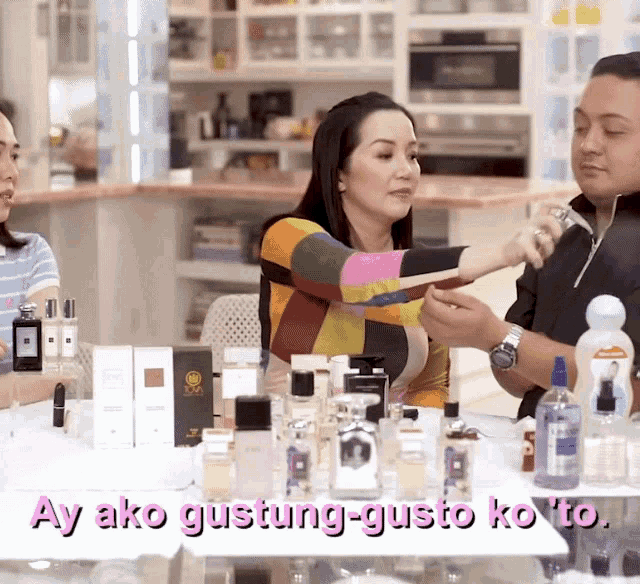 a group of people are sitting at a table with bottles of perfume and the words ay ako gustung-gusto ko to