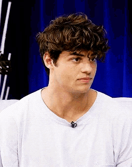 a young man with curly hair wearing a white t-shirt