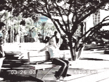 a woman sits on a bench in a park with the date 03-26-03