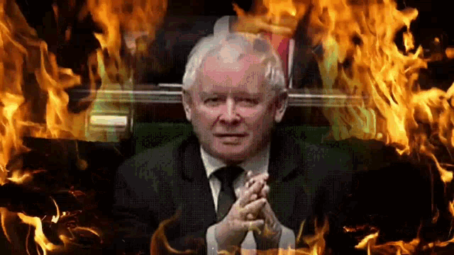a man in a suit and tie is surrounded by flames .